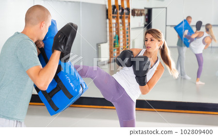 Young woman kicking boxing shield Young woman kicking boxing shield 102809400