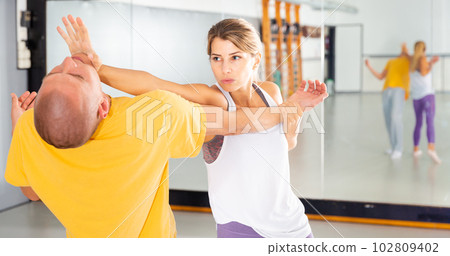 Woman performing palm heel strike while training in gym Woman performing palm heel strike while training in gym 102809402