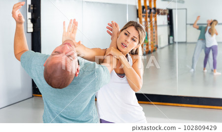 Woman performing palm heel strike while training in gym Woman performing palm heel strike while training in gym 102809429