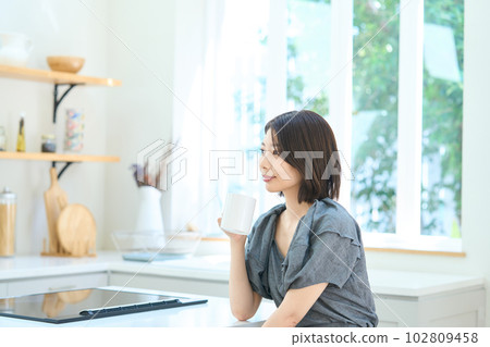 Young woman drinking coffee in dining kitchen Young woman drinking coffee in dining kitchen 102809458