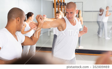 Two men practicing self defense techniques in gym Two men practicing self defense techniques in gym 102809469