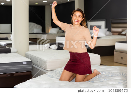 Smiling Latina delighted with new mattress 102809473