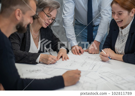 Brainstorming of four engineers and architects with blueprints in the office.  102811789