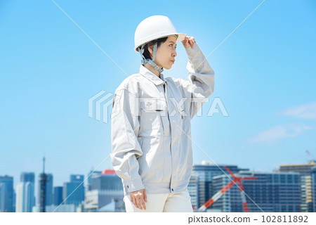 A woman wearing work clothes and checking a helmet A woman wearing work clothes and checking a helmet 102811892