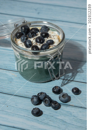 Glass jar with natural organic homemade yogurt and blueberries spirulina chlorella superfood super powder blue algae sea weed. Immunity-boosting ingredients. Concept of healthy eating breakfast of 102812289