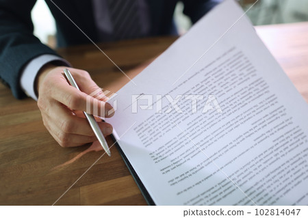 Male businessman attentively examines provisions of contract Male businessman attentively examines provisions of contract 102814047