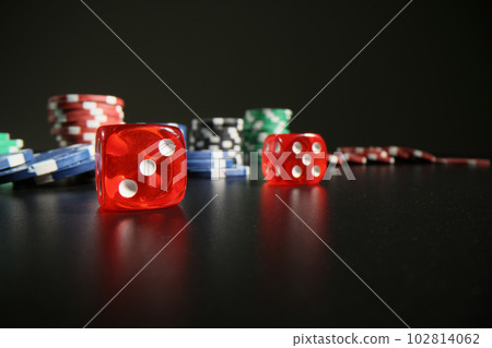 Red dice and colorful poker chips scattered on black table 102814062
