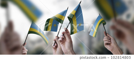 A group of people holding small flags of the Rwanda in their hands A group of people holding small flags of the Rwanda in their hands 102814803
