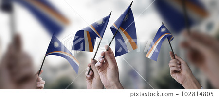 A group of people holding small flags of the Marshall in their hands A group of people holding small flags of the Marshall in their hands 102814805