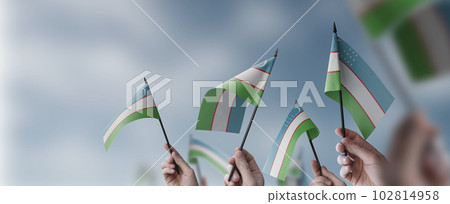 A group of people holding small flags of the Uzbekistan in their hands 102814958
