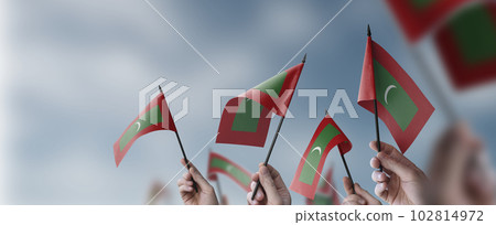 A group of people holding small flags of the Maldives in their hands A group of people holding small flags of the Maldives in their hands 102814972