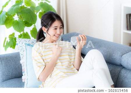 在房間裡操作智慧型手機的年輕女子 102815456