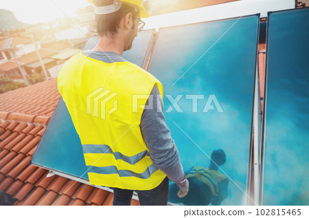 Man assembles solar panel for hot water in a roof 102815465