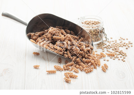 Green lentil fusilli pasta on a wooden background. 102815599
