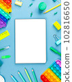 Top view arrangement album with white sheets and pens, pencils, paper clips and other office supplies on blue background 102816650