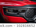 Red car headlights. Exterior detail. Close up detail on one of the LED headlights modern car. 102816652