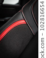 close-up black and red  perforated leather car seat. Skin texture 102816654