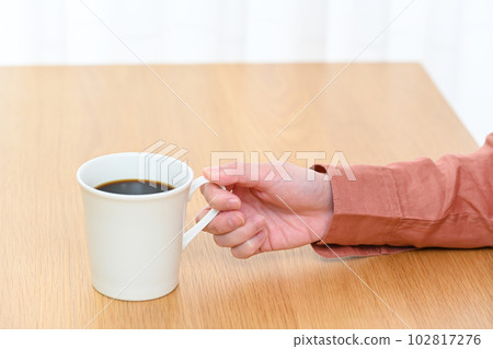 桌上拿著咖啡杯的年輕女人的手 桌上拿著咖啡杯的年輕女人的手 102817276