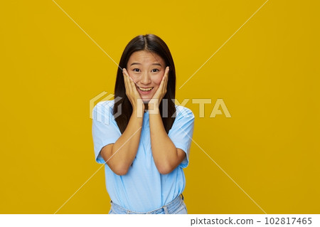 Asian woman smile with teeth hand gestures, signs and symbols on yellow background in blue t-shirt and jeans Asian woman smile with teeth hand gestures, signs and symbols on yellow background in blue t-shirt and jeans 102817465