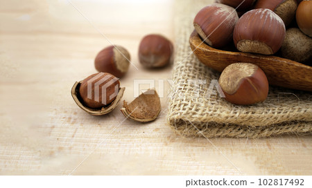Hazelnuts beside the jute sack on wooden table Hazelnuts beside the jute sack on wooden table 102817492
