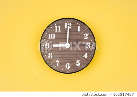 The Retro wooden clock at 9 O' clock on yellow color background. 102817497