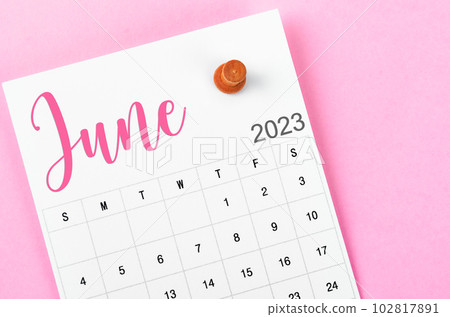 A June 2023 calendar and wooden push pin on pink colour background. A June 2023 calendar and wooden push pin on pink colour background. 102817891