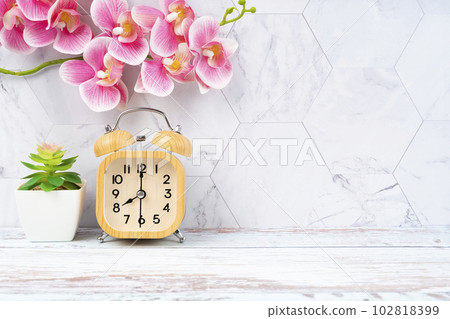 The Wooden alarm clock and pink color orchid on wooden floor with copy space for your design. 102818399