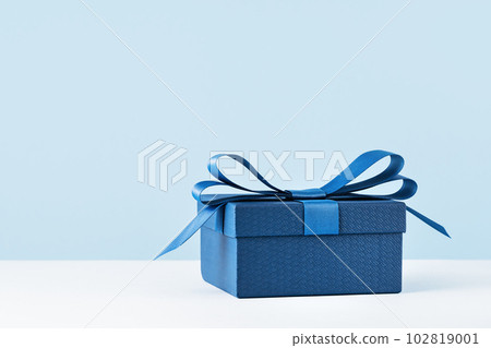 small Luxury gift box with a blue bow on light blue. Side view monochrome . Fathers day or Valentines day gift for him. Corporate gift concept or birthday party. Festive sale copy space small Luxury gift box with a blue bow on light blue. Side view monochrome . Fathers day or Valentines day gift for him. Corporate gift concept or birthday party. Festive sale copy space 102819001