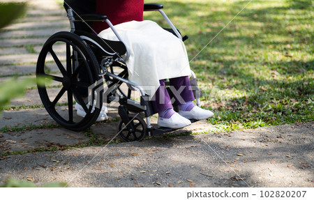 Nursing home. Young caregiver helping senior woman in wheelchair. 102820207