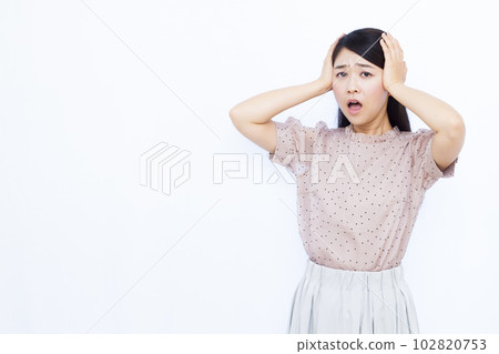Surprised woman in her 30s holding her head in front of a white background Surprised woman in her 30s holding her head in front of a white background 102820753