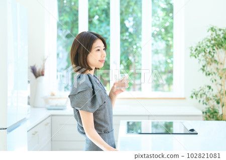 廚房裡拿著杯子的年輕女人 102821081