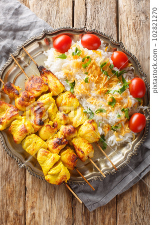 Joojeh kabab is a classic Persian chicken kebob with rice closeup on the plate. Vertical top view 102821270
