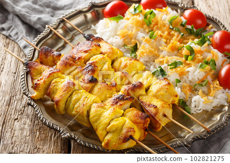 Persian Jujeh kabab is an Iranian dish that consists of grilled chunks of chicken marinated in saffron and yogurt served with rice closeup on the plate. Horizontal 102821275