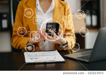SDK  Software development kit programming language technology concept, Person typing laptop computer and tablet with SDK icon on virtual screen. . 102823933