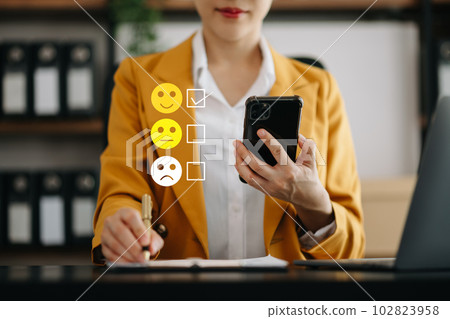 Smart Asian woman use smartphone and tablet choosing happy smile face icon. feedback rating and positive customer review experience, mental health assessment. world mental health day concept 102823958