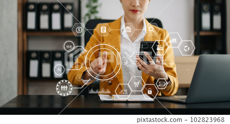 Businesswoman hand working digital marketing media in virtual screen with mobile phone and modern compute with VR icon diagram at office. 102823968