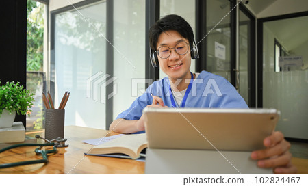 Medical student wearing headphone using digital tablet, preparing for university exams. Medical internship concept 102824467