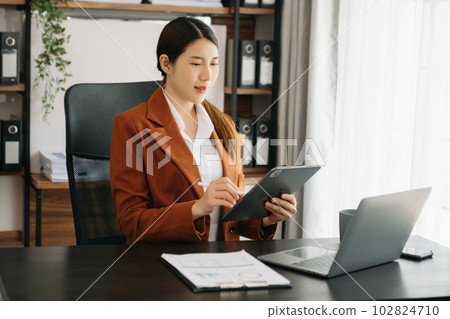 Business woman using tablet and laptop for doing math finance on an office desk, tax, report, accounting, statistics, and analytical research concept in office. Business woman using tablet and laptop for doing math finance on an office desk, tax, report, accounting, statistics, and analytical research concept in office. 102824710