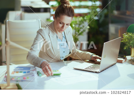 business woman in light business suit in green office 102824817