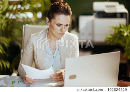 pensive 40 years old business owner woman in green office 102824819