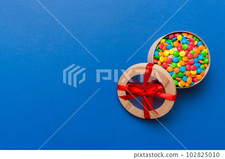 Set of different sweet candy in a paper box with a satin ribbon on a colored background. Holiday concept Set of different sweet candy in a paper box with a satin ribbon on a colored background. Holiday concept 102825010
