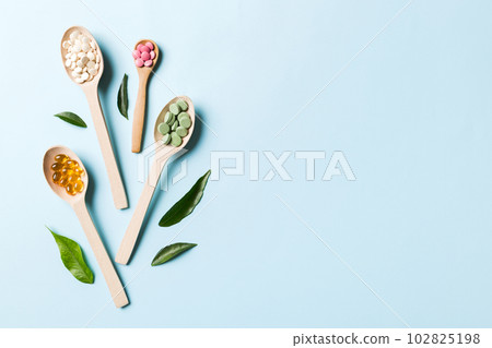 Top view Variety of vitamin and mineral pills in wooden spoon on Colored background. Top view of assorted pharmaceutical medicine pills. Dietary supplement healthcare product Top view Variety of vitamin and mineral pills in wooden spoon on Colored background. Top view of assorted pharmaceutical medicine pills. Dietary supplement healthcare product 102825198