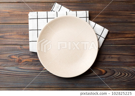 Top view on colored background empty round white plate on tablecloth for food. Empty dish on napkin with space for your design Top view on colored background empty round white plate on tablecloth for food. Empty dish on napkin with space for your design 102825225