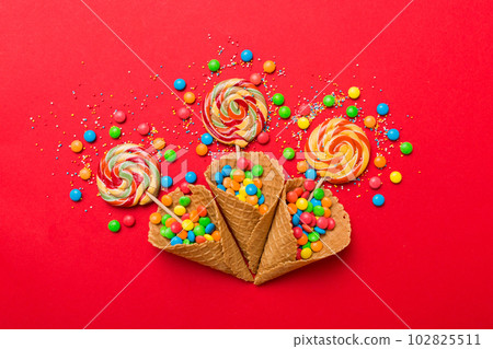 waffle cone full of assorted traditional candies falling out on colored background with copy space. Happy Holidays sale concept 102825511