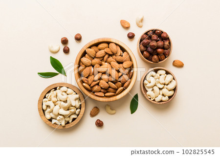 Assortment of nuts in wooden bowl on colored table. Cashew, hazelnuts, walnuts, almonds. Mix of nuts Top view with copy space Assortment of nuts in wooden bowl on colored table. Cashew, hazelnuts, walnuts, almonds. Mix of nuts Top view with copy space 102825545