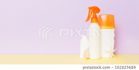 Beach accessories. Moisturiser sunscreen suntan lotion bottle for UVB skincare protection in summer with seashells on colored background. Mock up with copy space Beach accessories. Moisturiser sunscreen suntan lotion bottle for UVB skincare protection in summer with seashells on colored background. Mock up with copy space 102825689