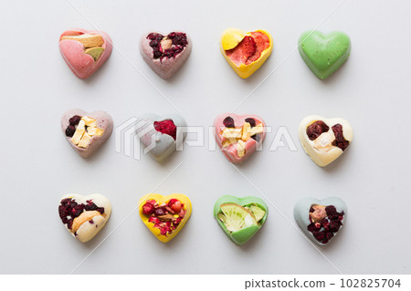 chocolate sweets in the form of a heart with fruits and nuts on a colored background. top view with space for text, holiday concept 102825704