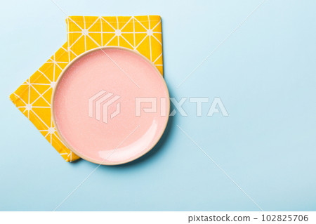 Top view on colored background empty round pink plate on tablecloth for food. Empty dish on napkin with space for your design Top view on colored background empty round pink plate on tablecloth for food. Empty dish on napkin with space for your design 102825706