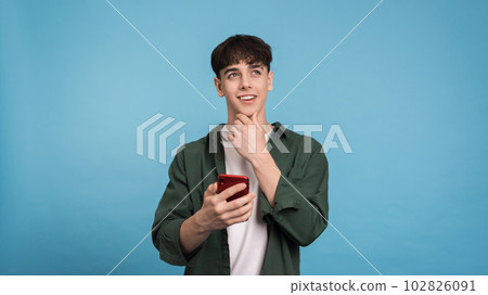 Young thinking man holding his phone 102826091