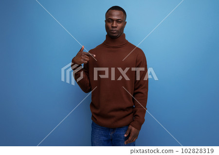 dark-skinned 25 year old guy with a short haircut in a brown sweater laughs on a studio background 102828319